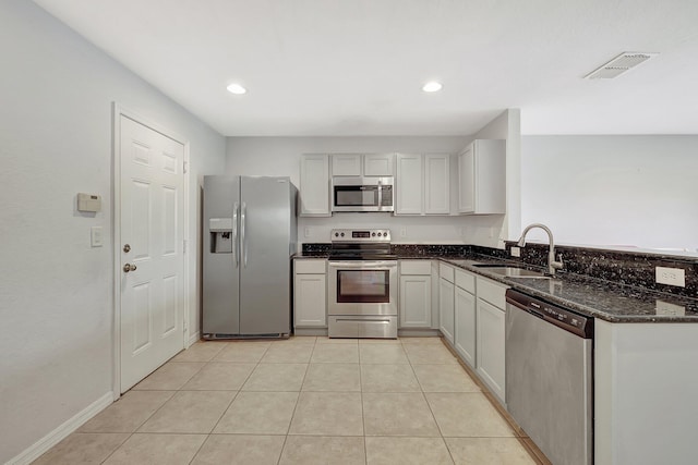 kitchen featuring kitchen peninsula, appliances with stainless steel finishes, dark stone counters, sink, and light tile patterned floors