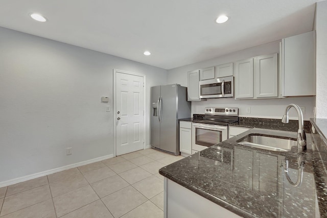 kitchen with white cabinetry, sink, stainless steel appliances, dark stone counters, and light tile patterned flooring