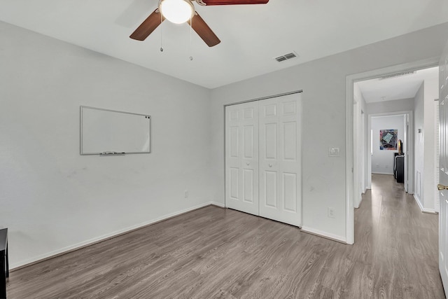 unfurnished bedroom with ceiling fan, light wood-type flooring, and a closet