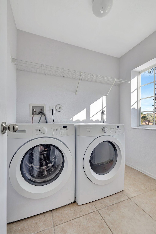 clothes washing area featuring washer and dryer and light tile patterned flooring