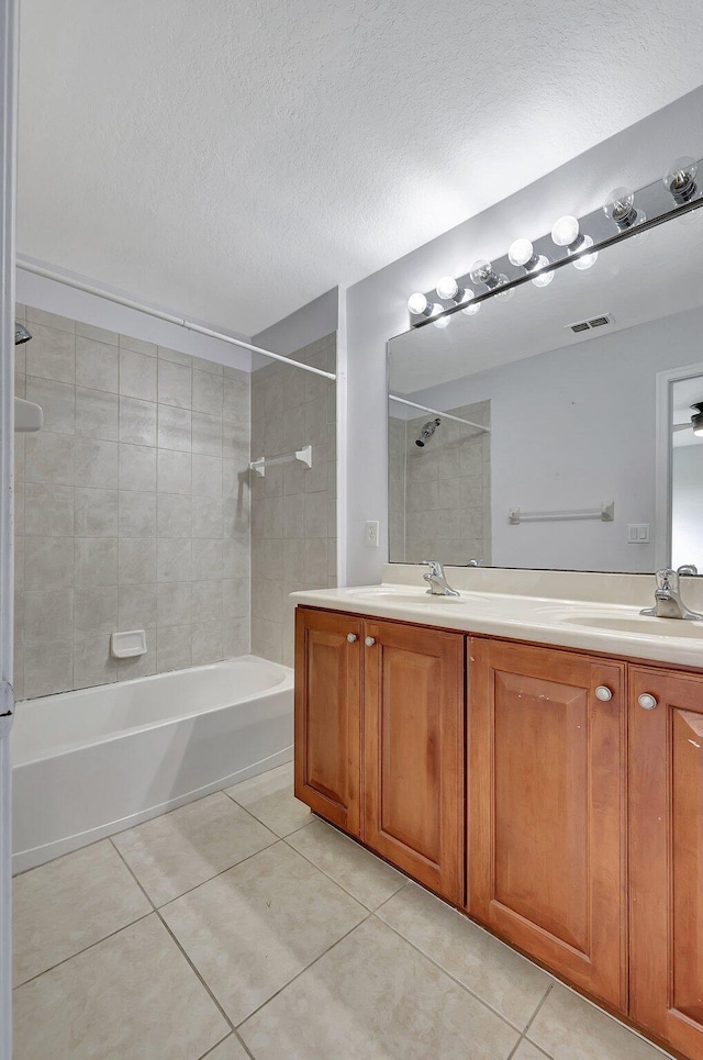 bathroom with tile patterned floors, a textured ceiling, vanity, and tiled shower / bath combo