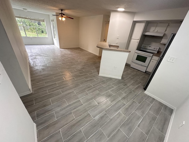 kitchen featuring ceiling fan, open floor plan, wood tiled floor, light countertops, and white range with electric cooktop