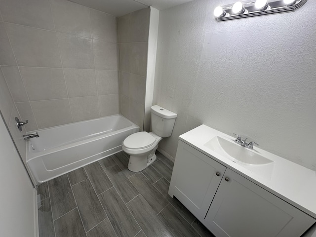 bathroom with a textured wall, toilet, wood tiled floor, vanity, and shower / washtub combination