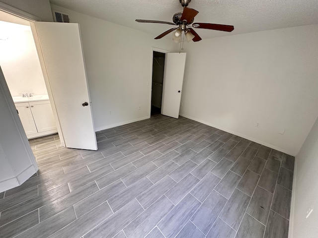 unfurnished room with a ceiling fan, wood tiled floor, visible vents, and a textured ceiling