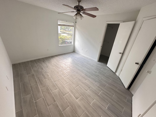 unfurnished bedroom with a textured ceiling, wood finish floors, and baseboards