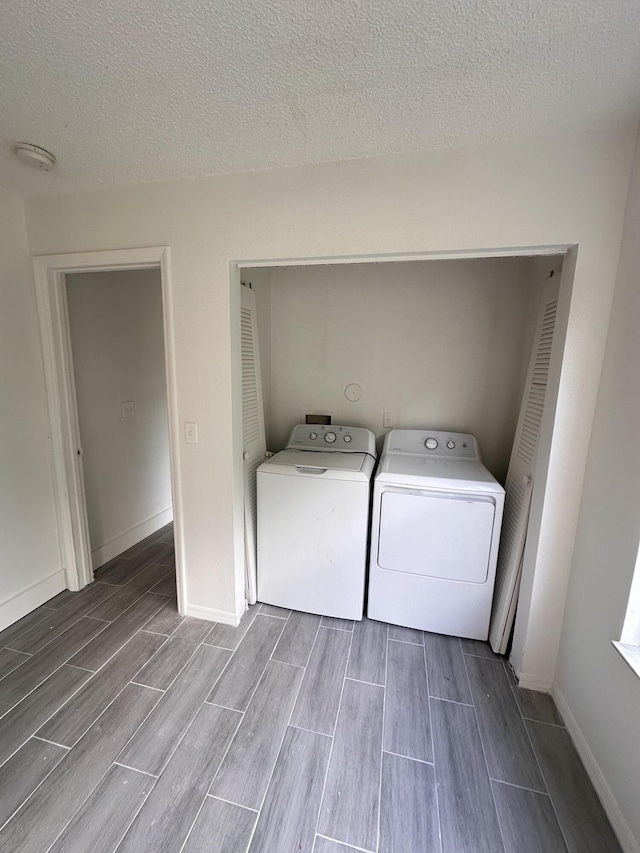 laundry room featuring washer and clothes dryer, wood tiled floor, a textured ceiling, laundry area, and baseboards