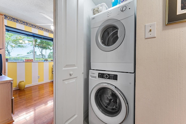 laundry room featuring stacked washer and dryer, hardwood / wood-style floors, and a textured ceiling