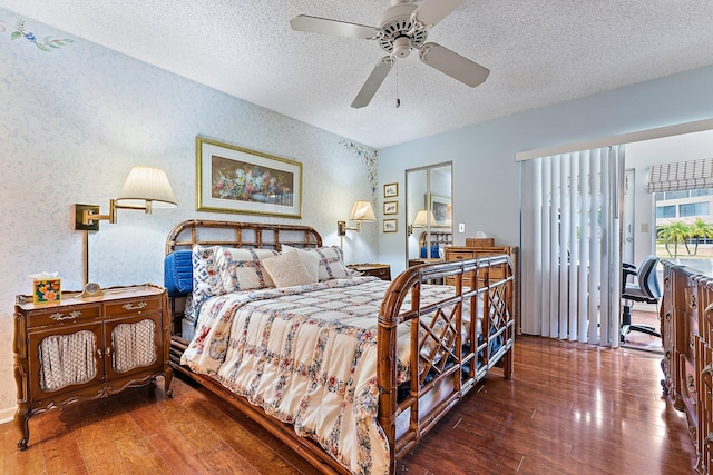 bedroom with a textured ceiling, ceiling fan, and dark wood-type flooring