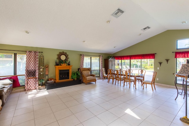 living room with a wealth of natural light, light tile patterned floors, and vaulted ceiling