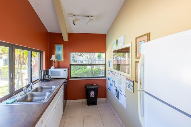 kitchen featuring white appliances, white cabinets, lofted ceiling with beams, sink, and light tile patterned floors