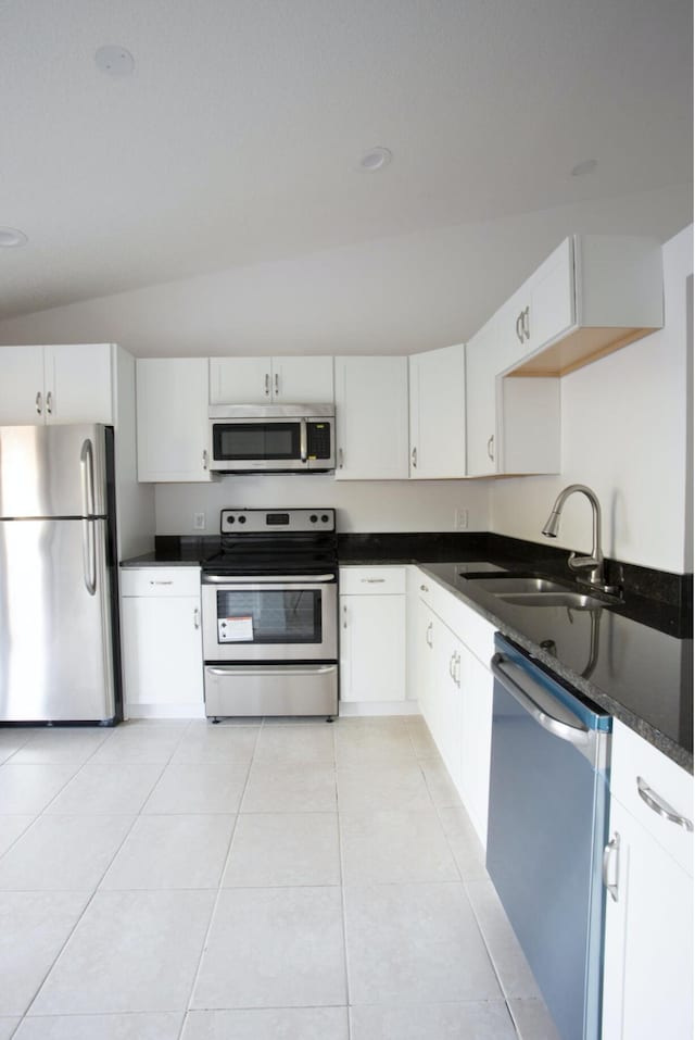 kitchen with white cabinets, sink, vaulted ceiling, light tile patterned floors, and appliances with stainless steel finishes