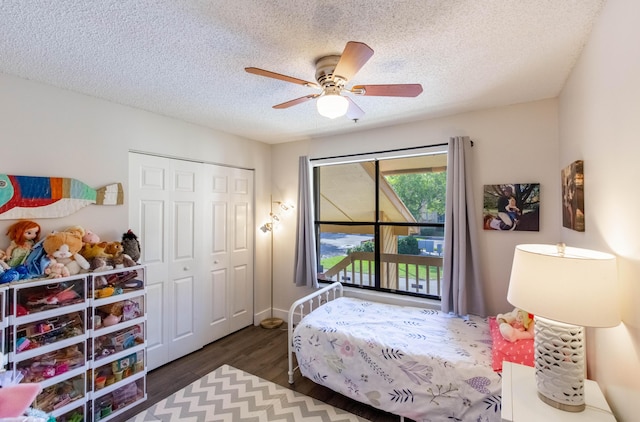 bedroom with ceiling fan, dark hardwood / wood-style flooring, a textured ceiling, and a closet