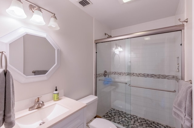 bathroom with vanity, toilet, and a shower with shower door