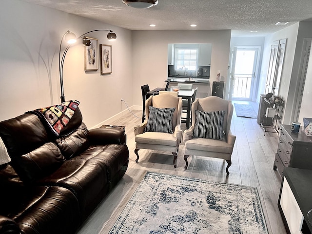 living room with light hardwood / wood-style flooring, a textured ceiling, and sink