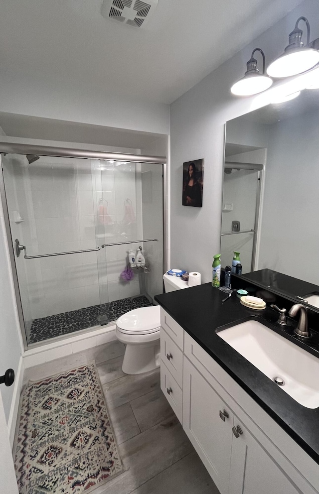 bathroom with walk in shower, vanity, and toilet