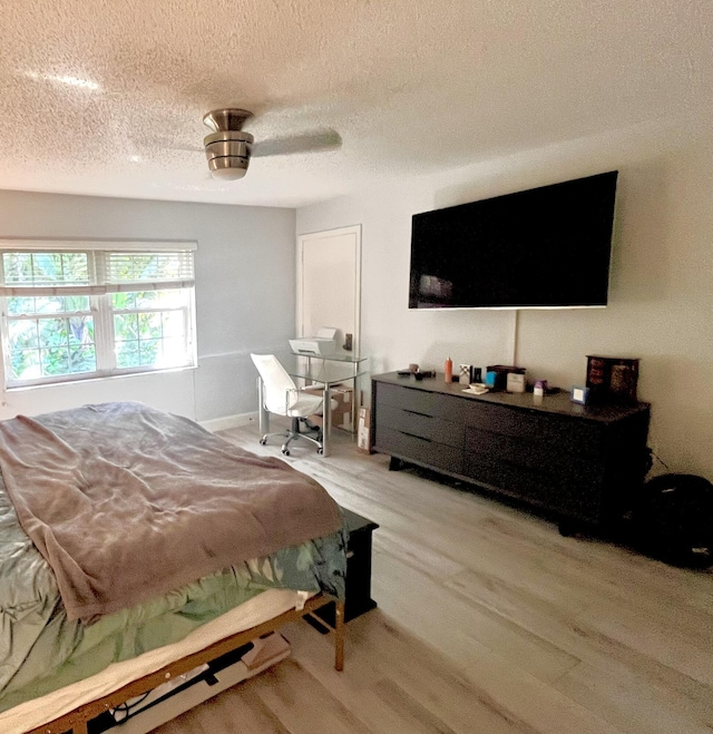 bedroom with ceiling fan, a textured ceiling, and light hardwood / wood-style flooring