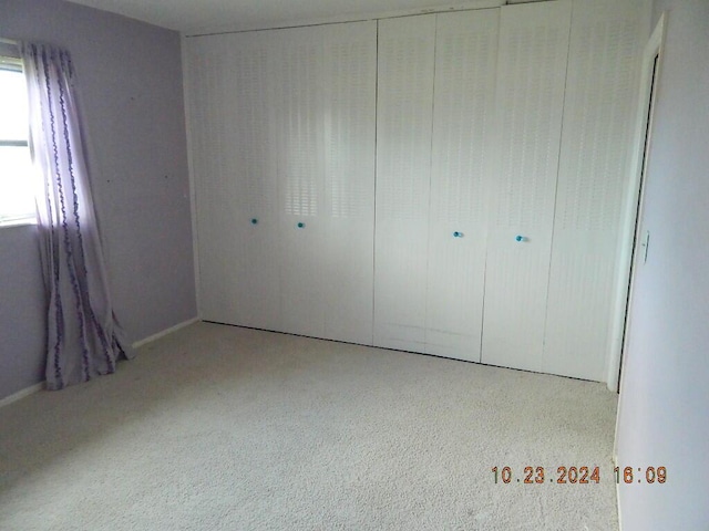 unfurnished bedroom with light carpet and a closet