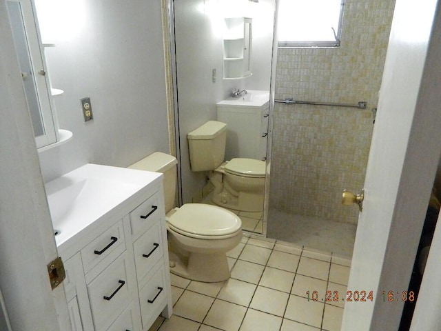 bathroom with tile patterned floors, vanity, toilet, and a tile shower