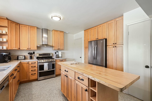 kitchen with sink, wall chimney range hood, butcher block countertops, a kitchen island, and appliances with stainless steel finishes