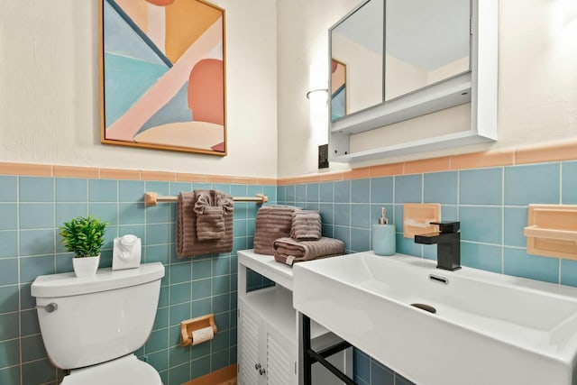 bathroom with toilet, tile walls, and sink