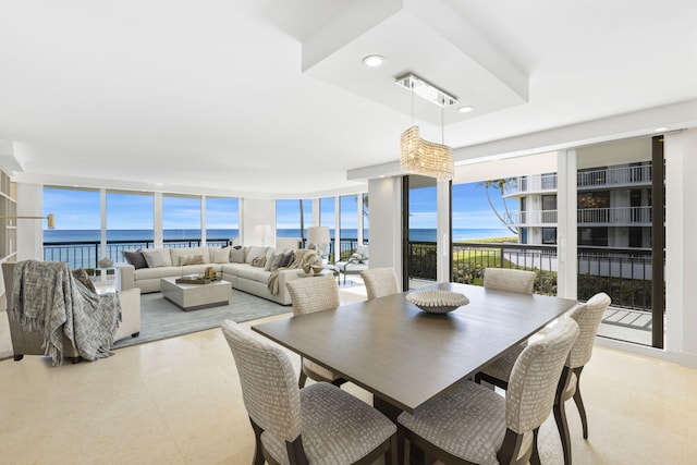 dining space featuring a wall of windows, a water view, and a raised ceiling