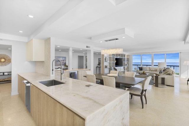 kitchen with light stone countertops, decorative light fixtures, light brown cabinets, wine cooler, and sink