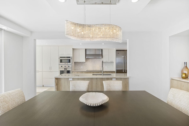 kitchen featuring a notable chandelier, decorative backsplash, sink, white cabinetry, and appliances with stainless steel finishes