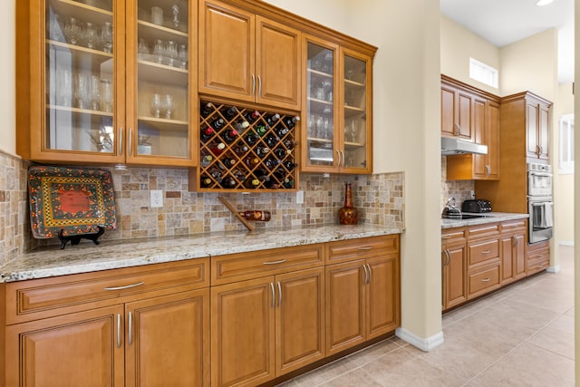 kitchen with tasteful backsplash, light tile patterned floors, black cooktop, stainless steel double oven, and light stone counters