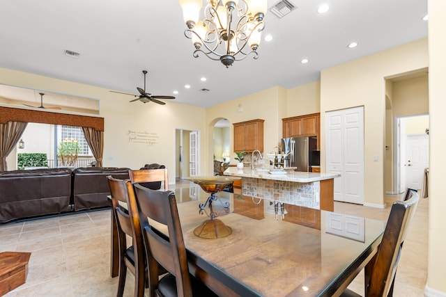 tiled dining room with ceiling fan with notable chandelier and sink