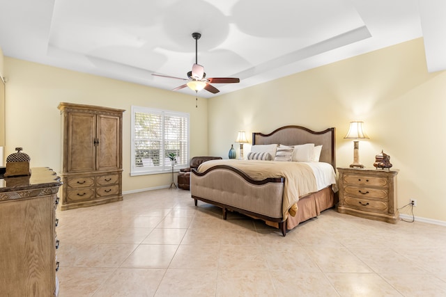 tiled bedroom featuring ceiling fan and a tray ceiling