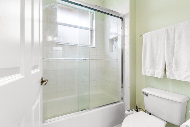 bathroom featuring enclosed tub / shower combo and toilet