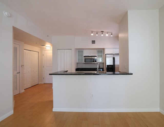 kitchen with kitchen peninsula, white cabinetry, stainless steel appliances, and light wood-type flooring