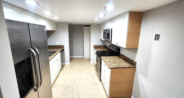 kitchen with dark stone counters, white cabinets, stainless steel appliances, and light tile patterned floors