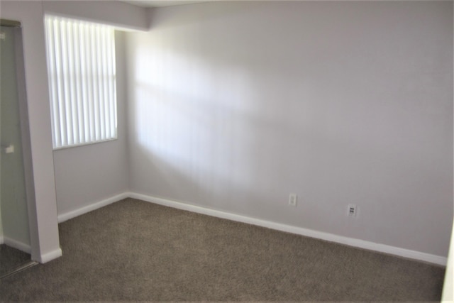 unfurnished room with dark colored carpet