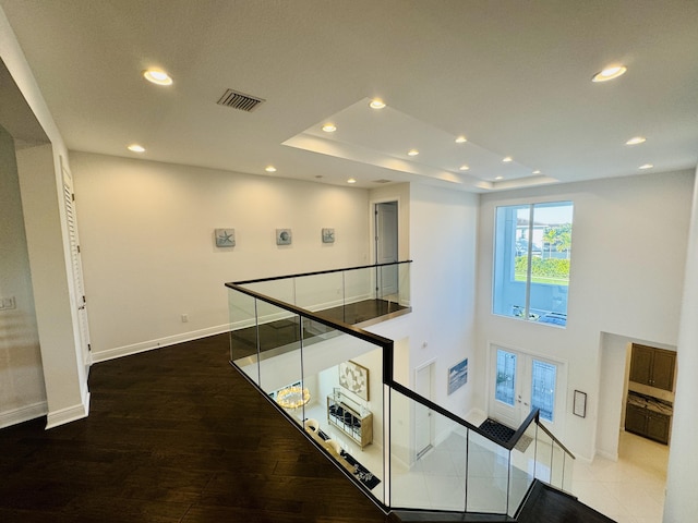 corridor with a raised ceiling, french doors, and wood-type flooring