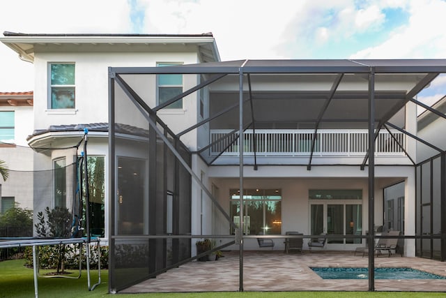 rear view of property with a lanai, a balcony, and a patio