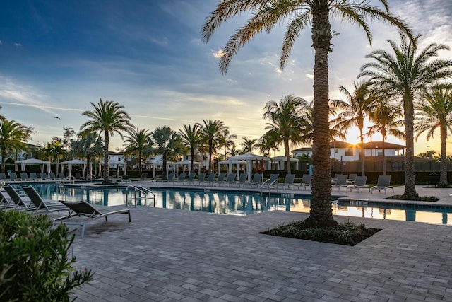 pool at dusk featuring a patio