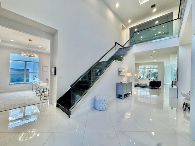 stairway featuring tile patterned floors, a notable chandelier, and a towering ceiling