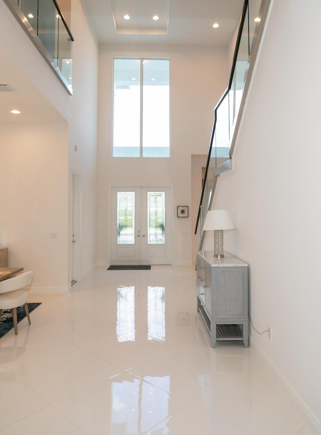 tiled living room with french doors and a towering ceiling