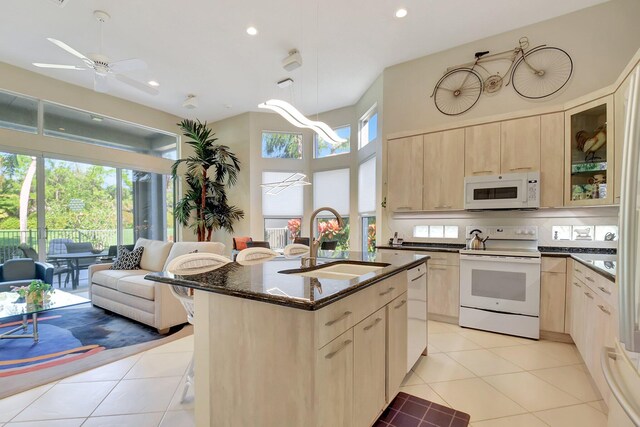 kitchen featuring ceiling fan, sink, an island with sink, white appliances, and light tile patterned floors