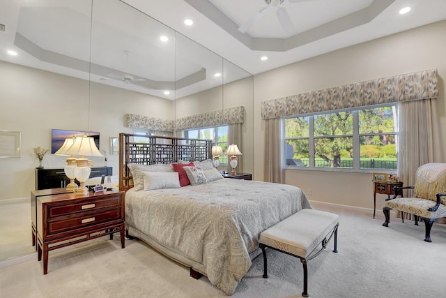 bedroom featuring carpet, a high ceiling, a tray ceiling, and ceiling fan