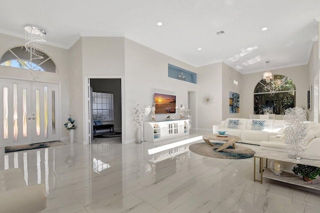 living room with a chandelier, a towering ceiling, and crown molding