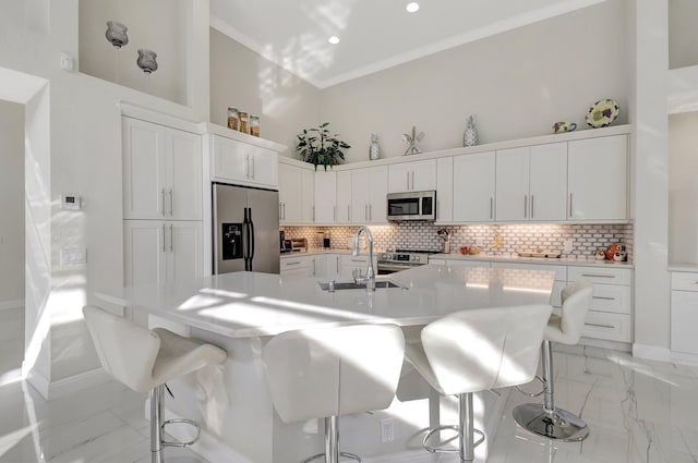 kitchen with a breakfast bar area, an island with sink, and appliances with stainless steel finishes