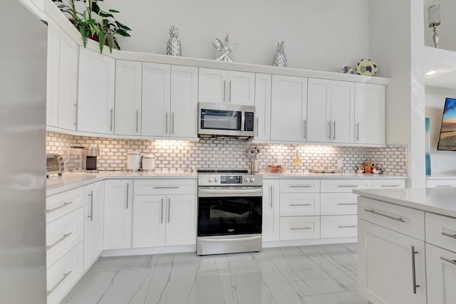 kitchen with white cabinets, appliances with stainless steel finishes, and backsplash