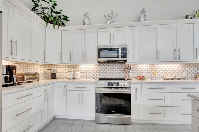 kitchen with appliances with stainless steel finishes, backsplash, and white cabinetry