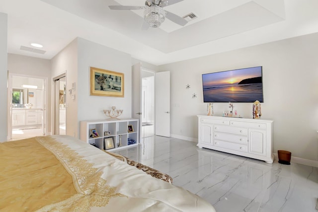 bedroom with a raised ceiling, ensuite bath, and ceiling fan