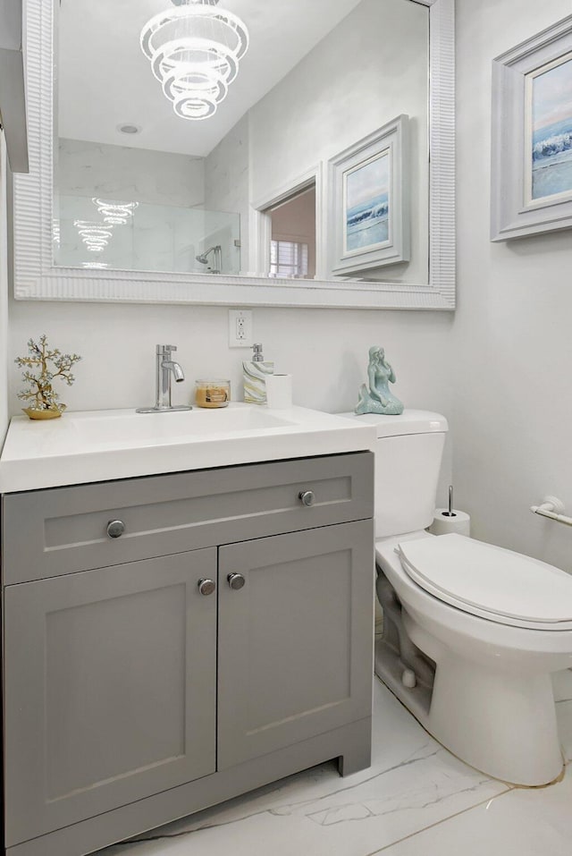 bathroom featuring vanity, toilet, a shower with shower door, and an inviting chandelier