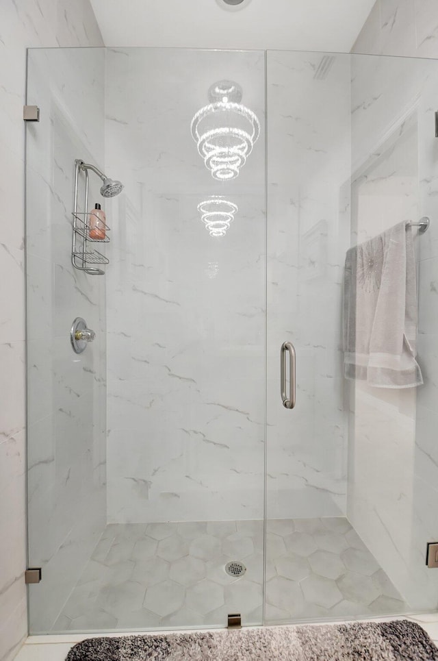 bathroom with a shower with shower door and a notable chandelier