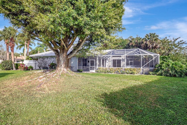 back of property with glass enclosure and a lawn