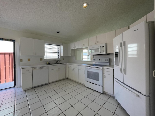 kitchen with sink, light tile patterned floors, a textured ceiling, white appliances, and white cabinets